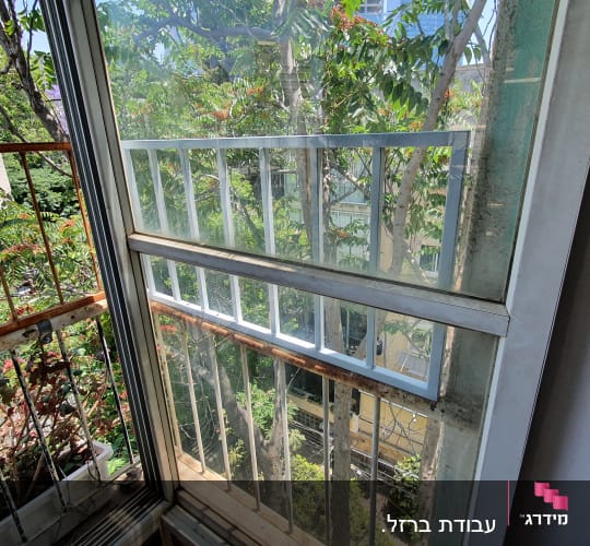 מסגרת חלון עם סורגים מתכתיים וחלון זכוכית